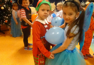 Dwoje dzieci tańczy z balonem ułożonym pomiędzy brzuchami.